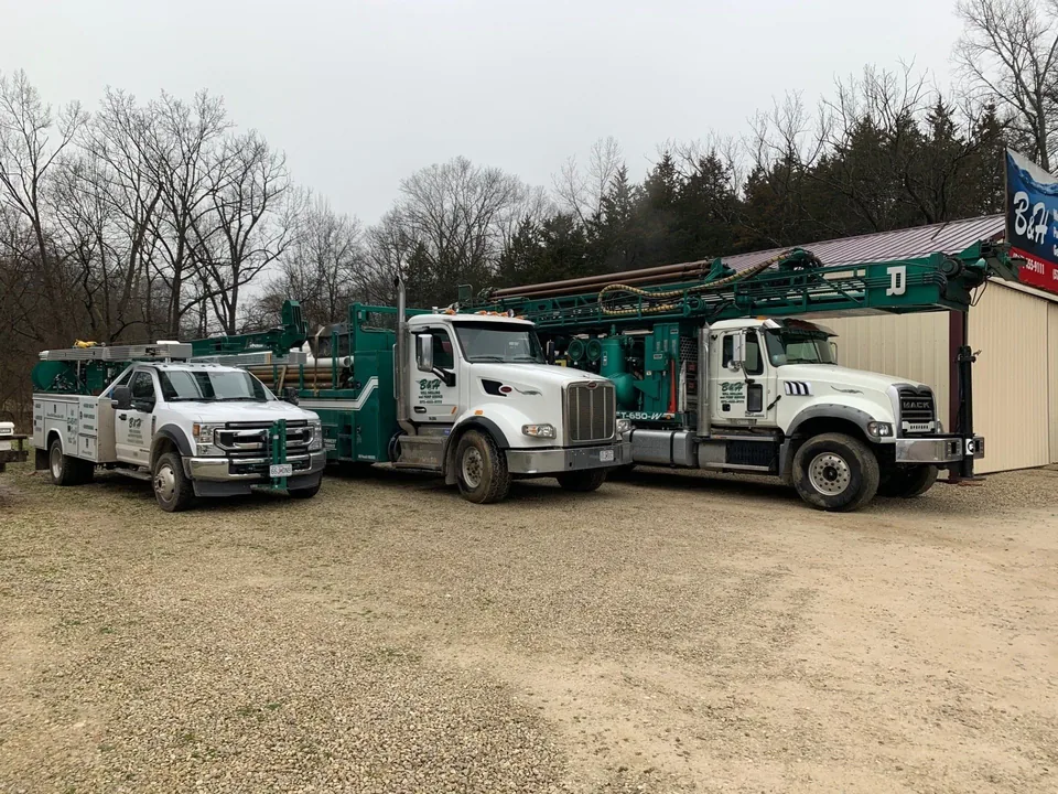 A B&H service truck and two rotary drilling rigs parked together at the yard