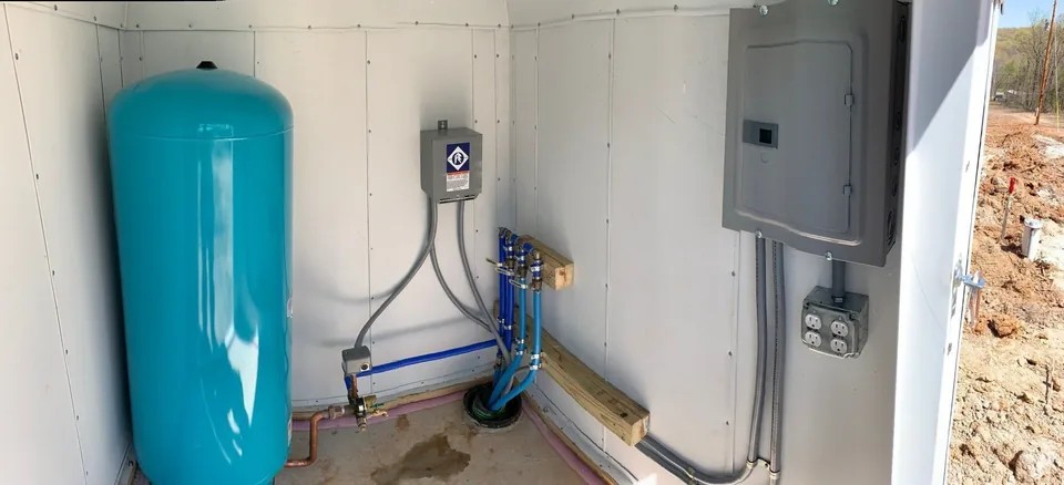 Inside a finished insulated well house: pressure tank, control box and electrical panel neatly piped